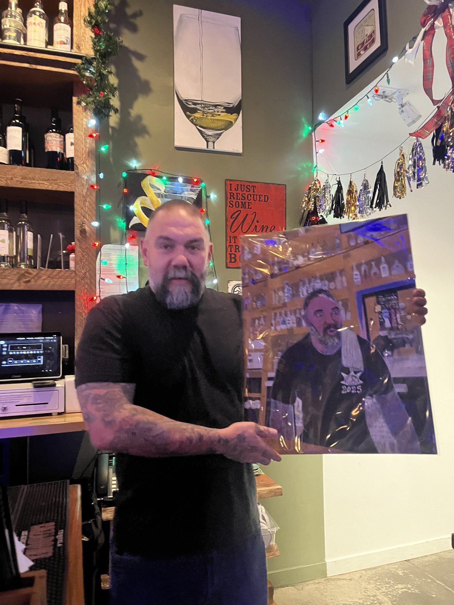 A man holds up a painted portrait behind the bar during the New Year’s Eve gathering.