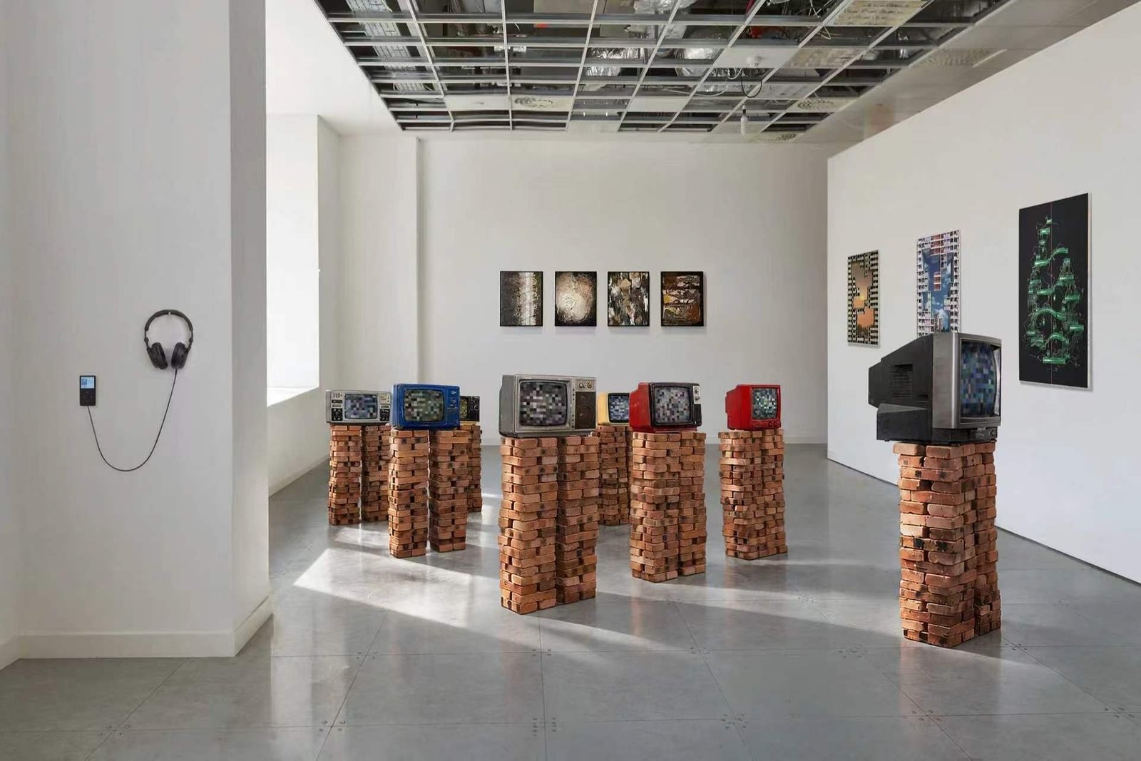 Gallery installation with CRT televisions on brick plinths and artworks on the walls