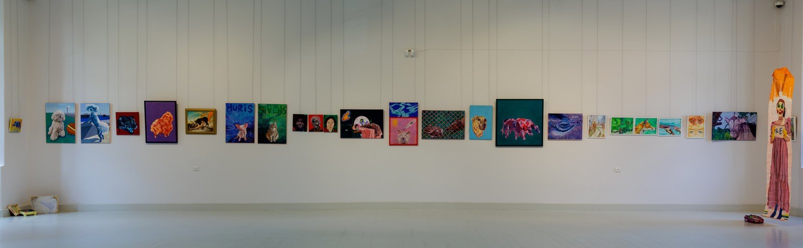 A panoramic view of colourful animal paintings displayed across a long gallery wall.