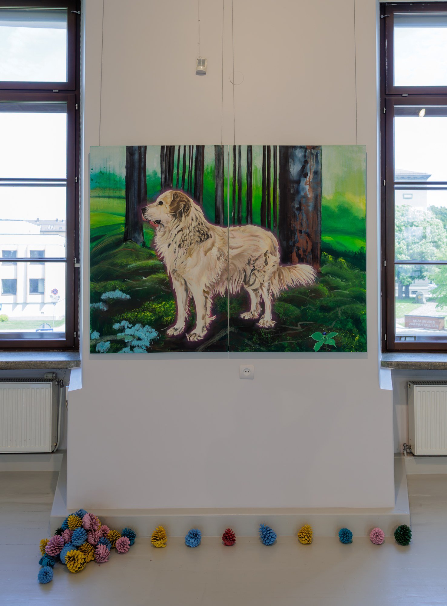 A painting of a pale dog in a green woodland displayed between gallery windows.