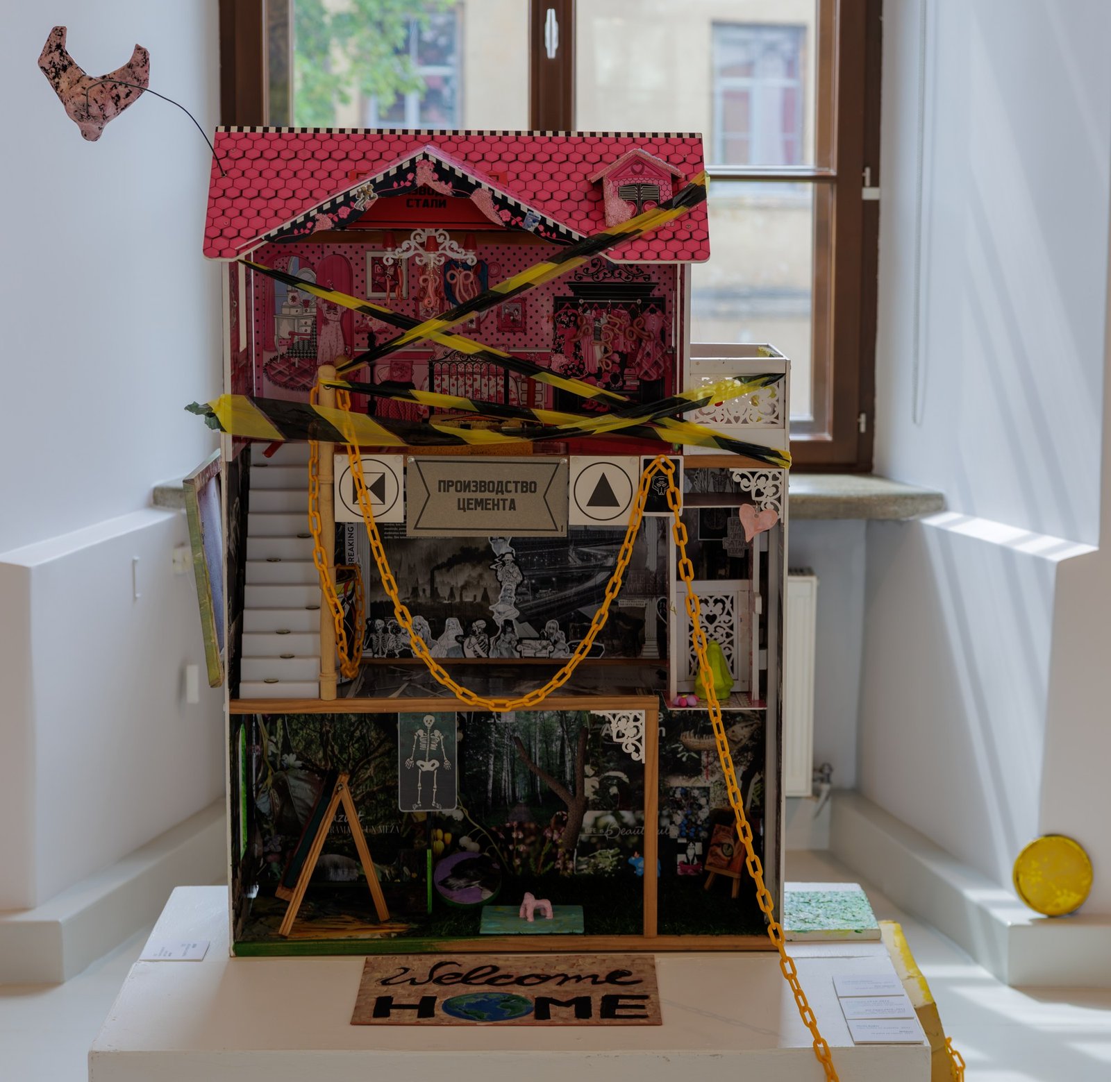An artwork installation built inside a salvaged doll house, displayed on a plinth.